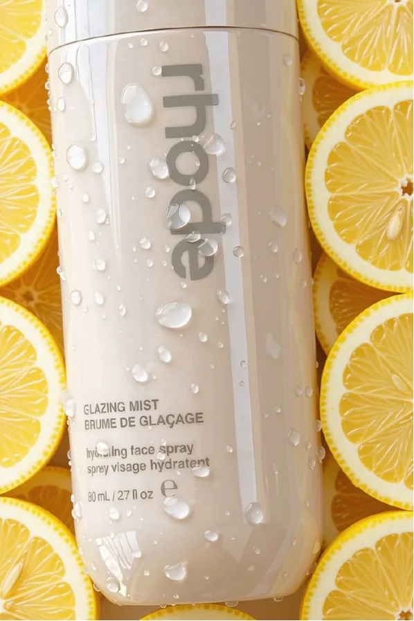 Rhode Glazing Mist bottle resting on sliced lemons.